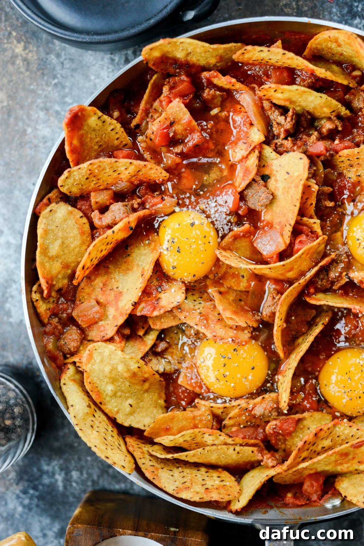 Hearty Chorizo and Sweet Potato Chilaquiles 15 Seasoning eggs with salt and pepper in the chilaquiles skillet