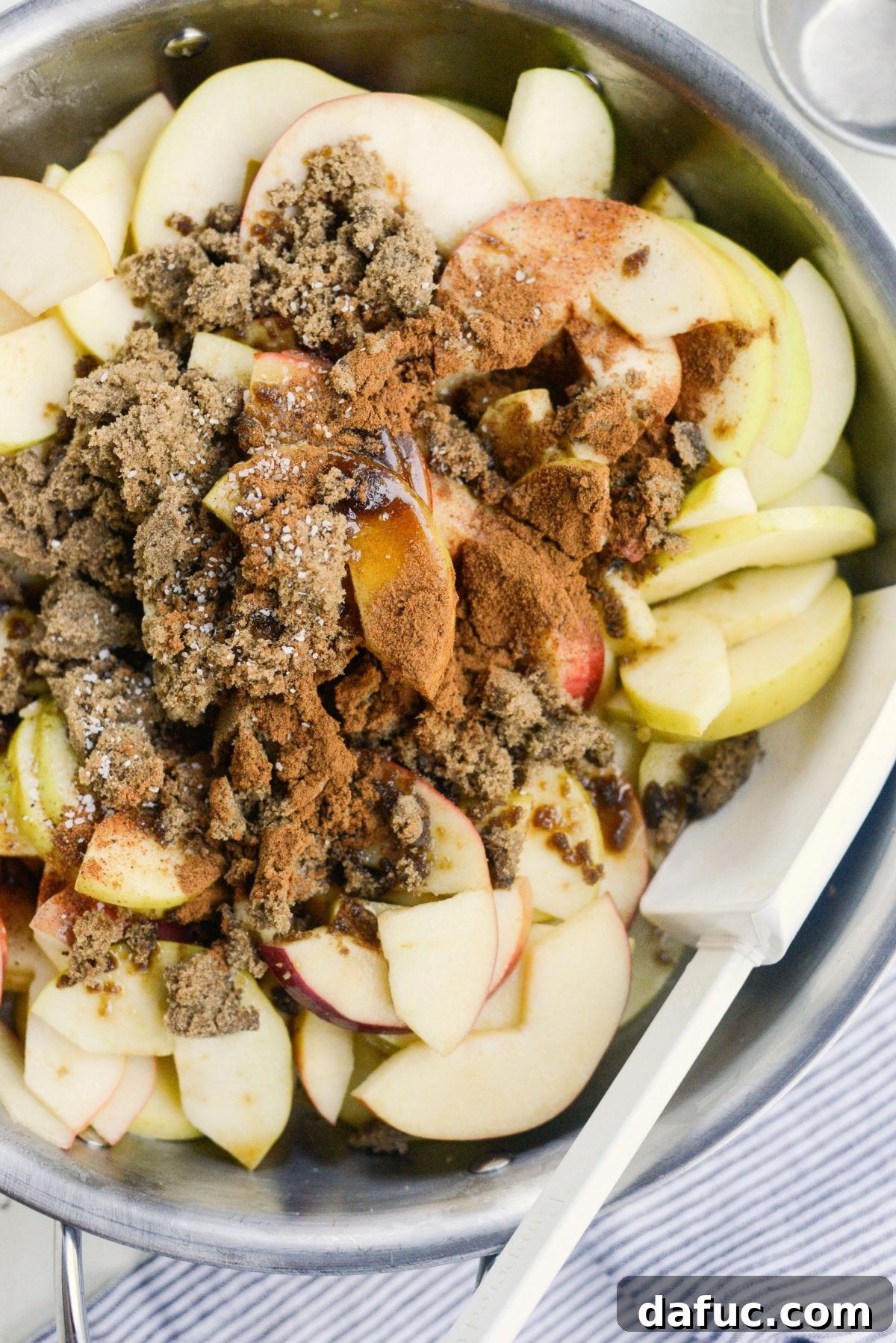 Lemon juice, brown sugar, cinnamon, nutmeg, and salt being added to the softened apples