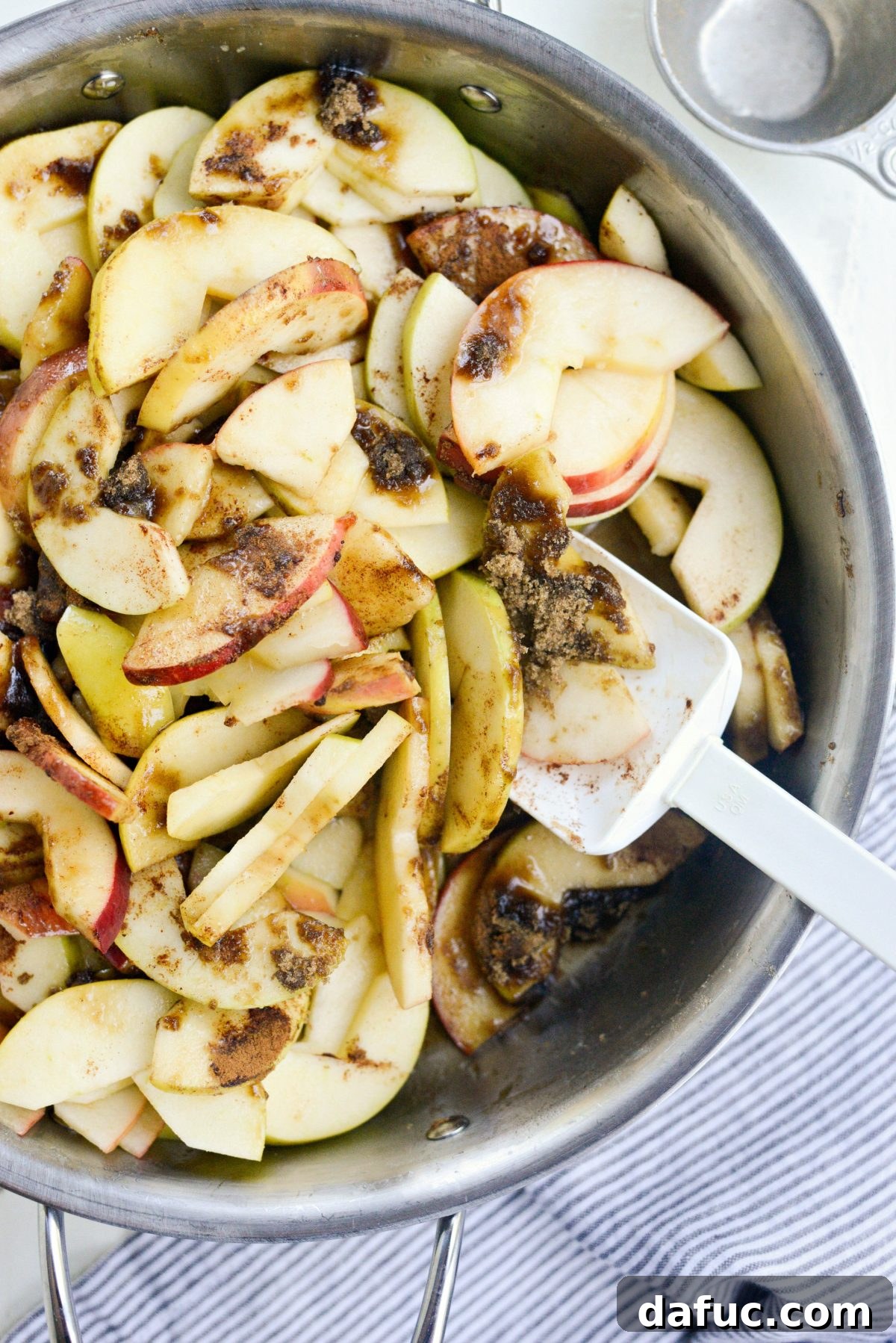 Apples being gently tossed with the added spices and sugar in the skillet