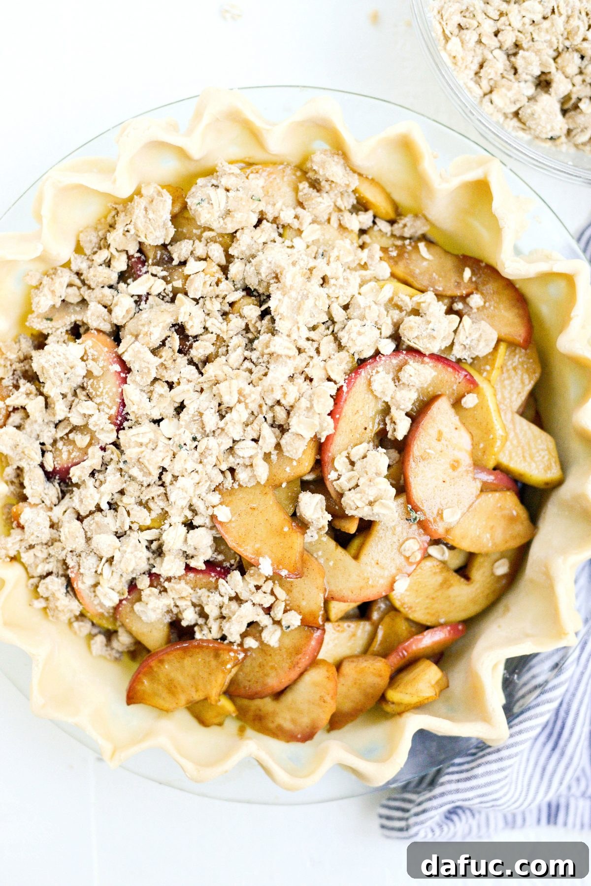 Oatmeal thyme crumble being sprinkled evenly over the apple filling