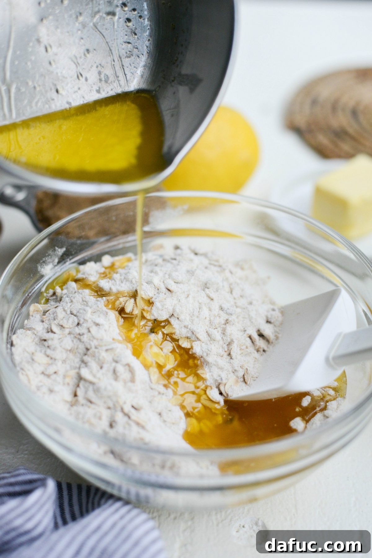 Melted butter being poured into the oatmeal and sugar mixture