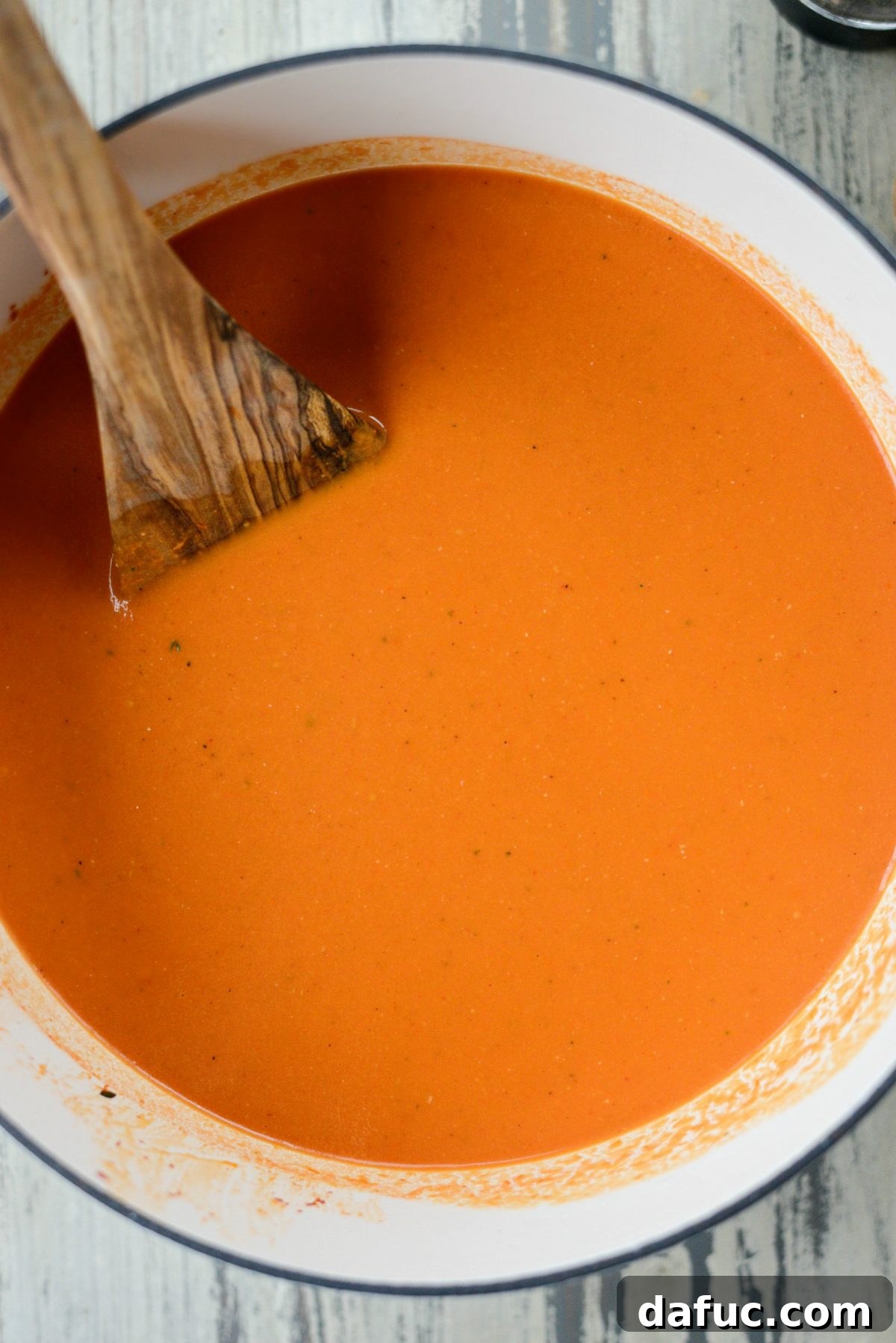 The finished Roasted Red Pepper Tomato Soup heating gently in a Dutch oven, its rich color promising deliciousness.