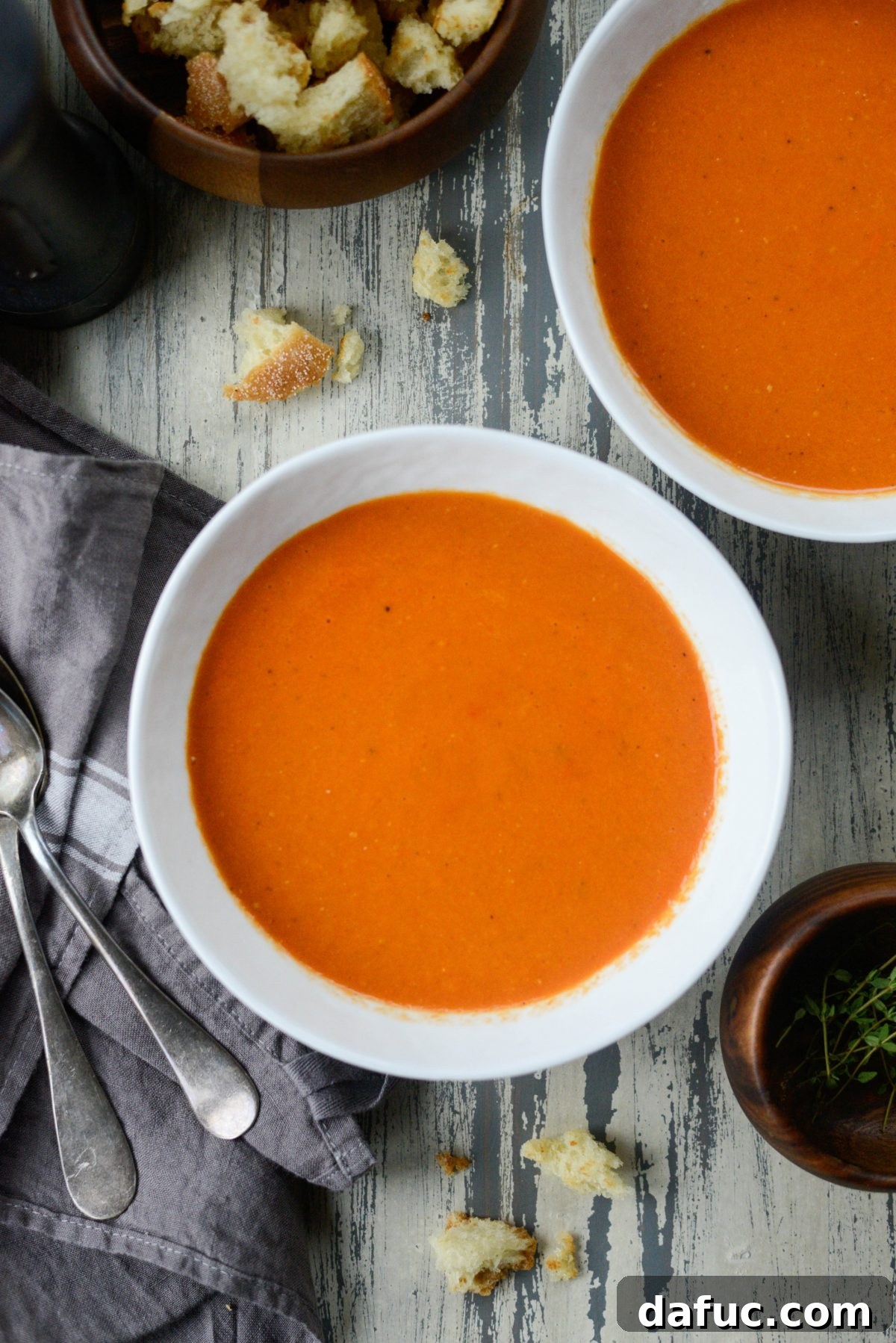 A ladle scooping a generous portion of hot Roasted Red Pepper Tomato Soup into a serving bowl.