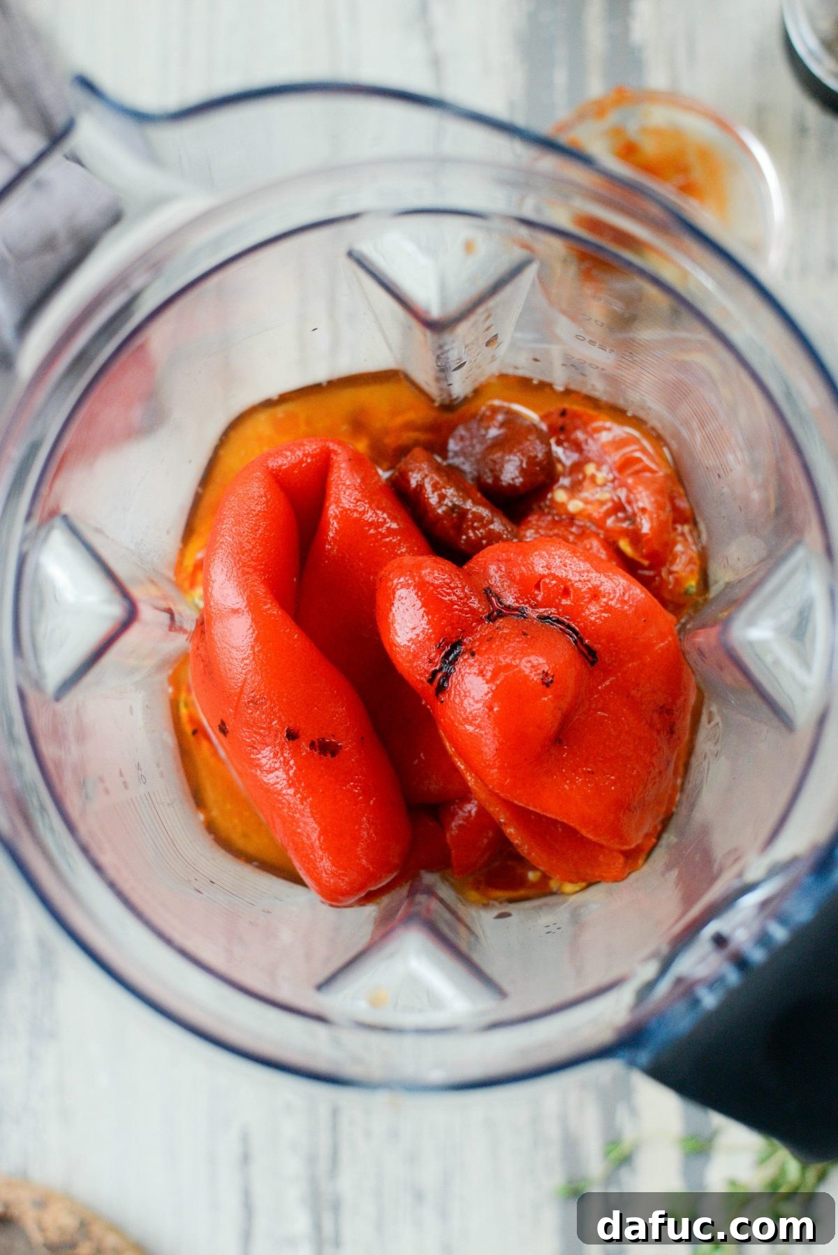 Close-up of roasted tomatoes, roasted red peppers, and chipotle peppers in a blender, ready to be pureed into soup.