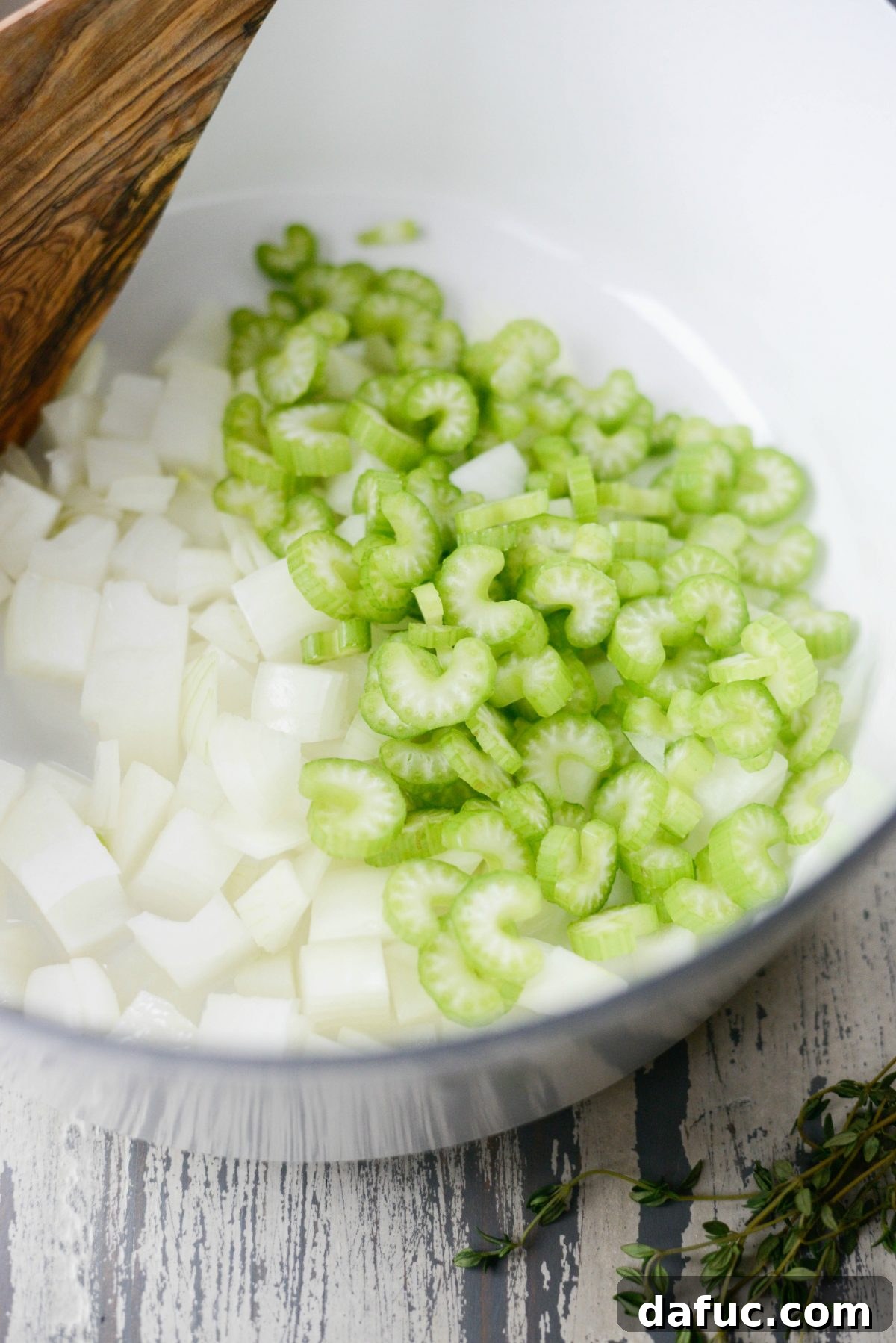 Diced onions and sliced celery sautéing in a Dutch oven with olive oil, softening for the soup base.