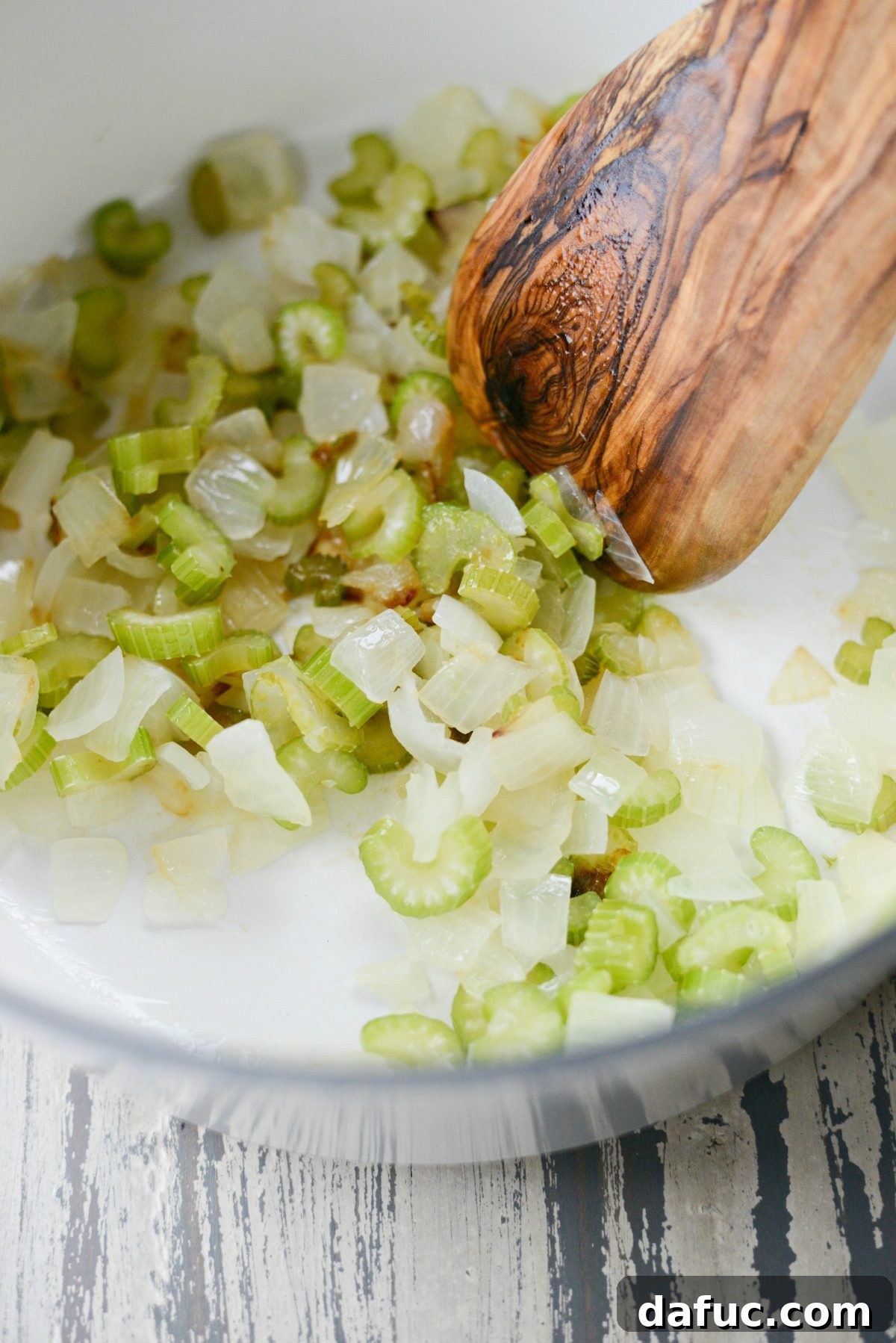Sautéed onions and celery gently caramelizing in a Dutch oven, creating a fragrant foundation for the soup.