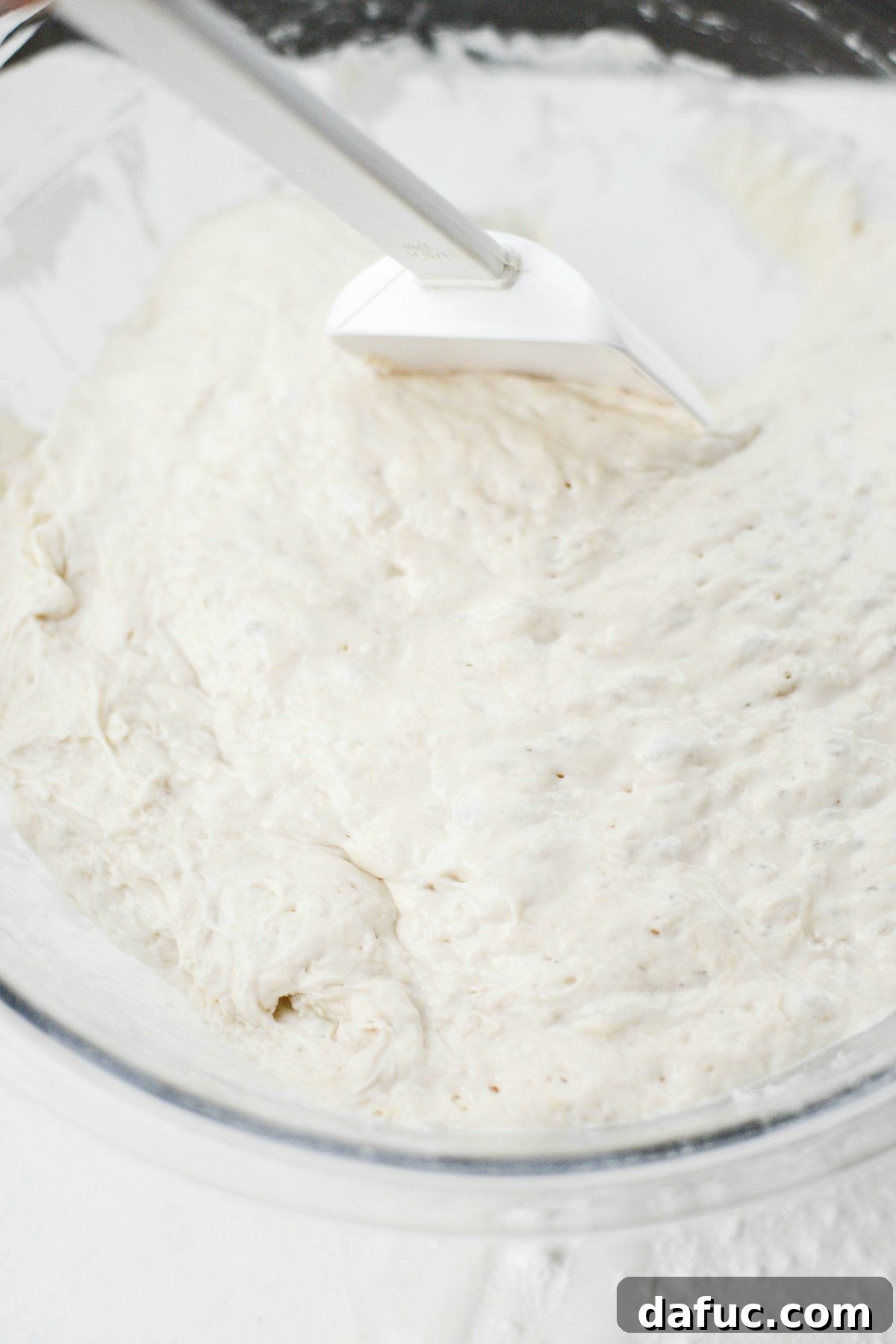 No-Knead Ciabatta: Easy Homemade Perfection 14 Using a spatula to loosen sticky ciabatta dough from the edges of a mixing bowl