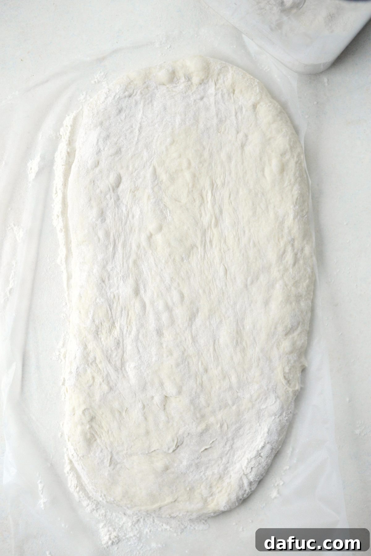 No-Knead Ciabatta: Easy Homemade Perfection 17 Shaping the ciabatta dough into a flat, elongated loaf on a floured surface