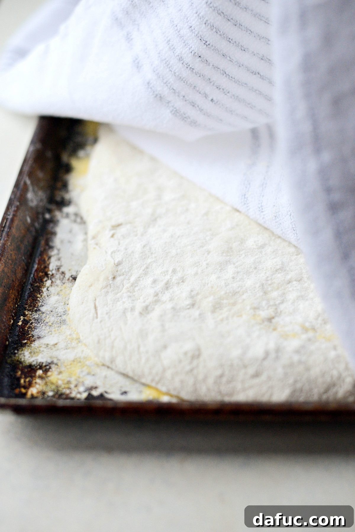 No-Knead Ciabatta: Easy Homemade Perfection 19 Ciabatta loaf covered with a kitchen towel for its second rise on a baking pan