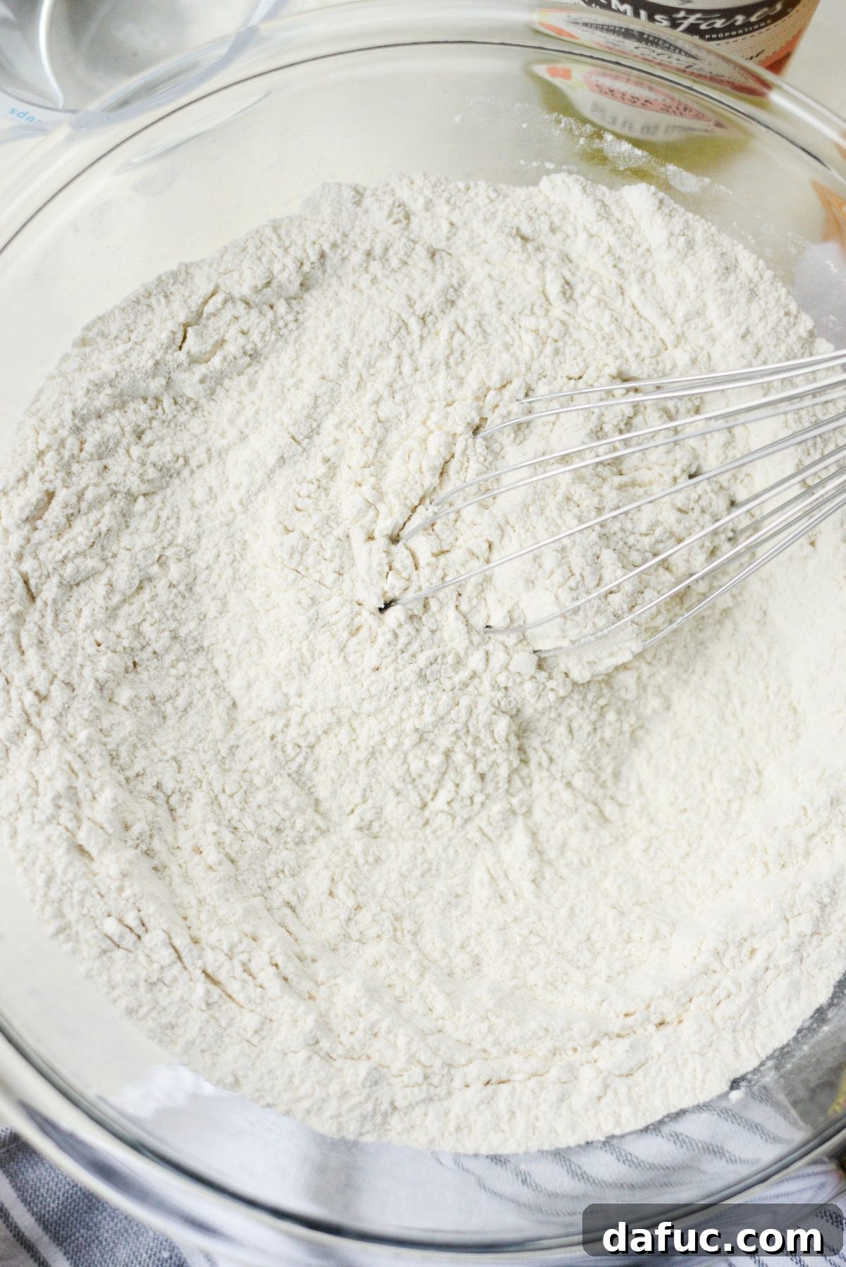 No-Knead Ciabatta: Easy Homemade Perfection 6 Hands whisking dry ingredients: flour, salt, and yeast in a large bowl