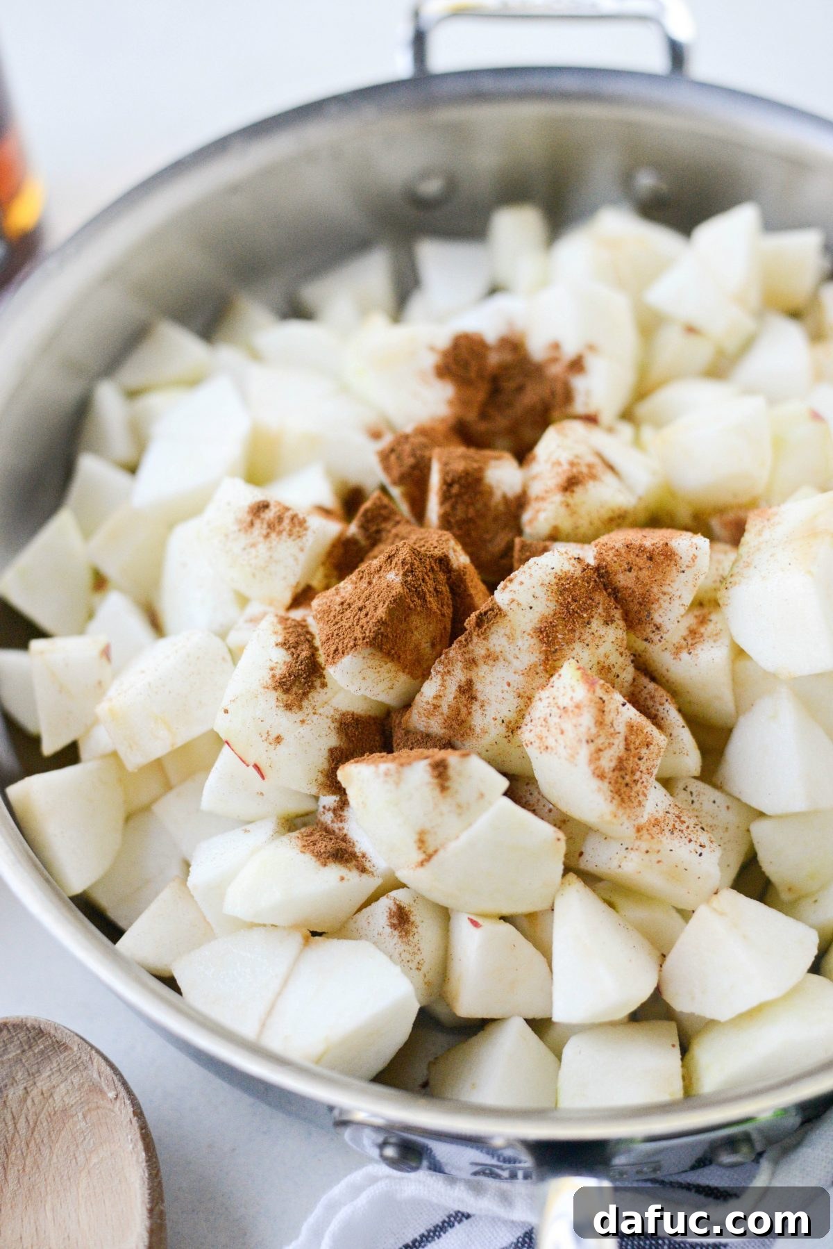 Adding lemon juice and warming spices to diced apples in a skillet.