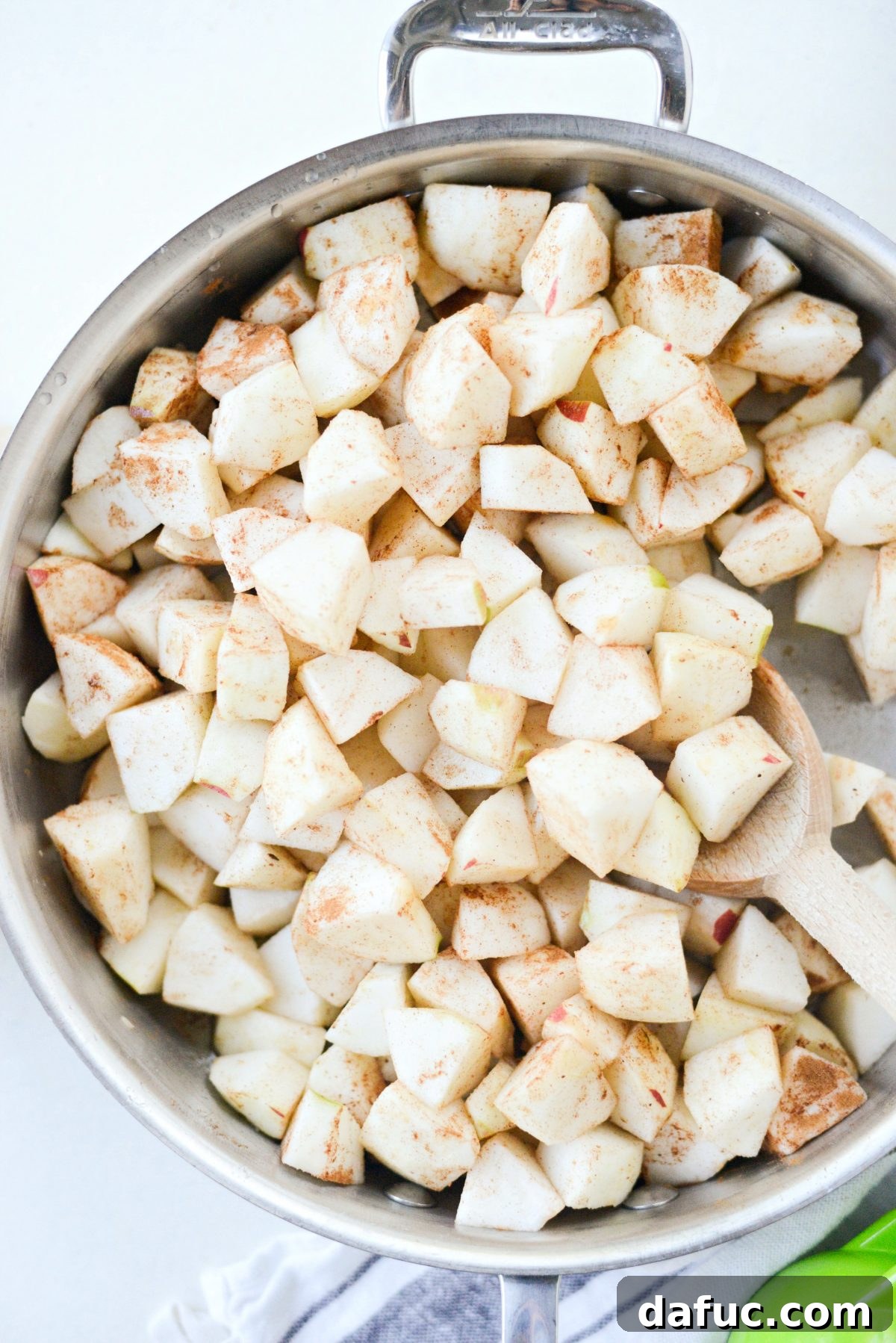 Diced apples tossed with spices and lemon juice in a skillet, ready for simmering.
