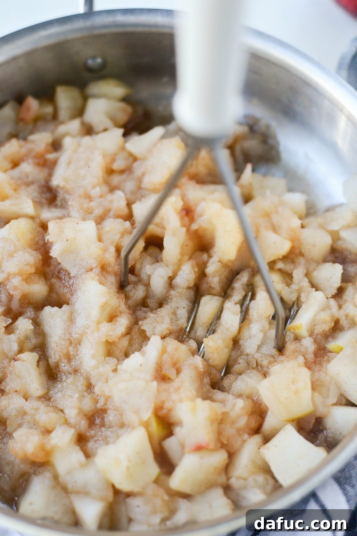 Cooked apples in a skillet, softened and ready for mashing into applesauce.