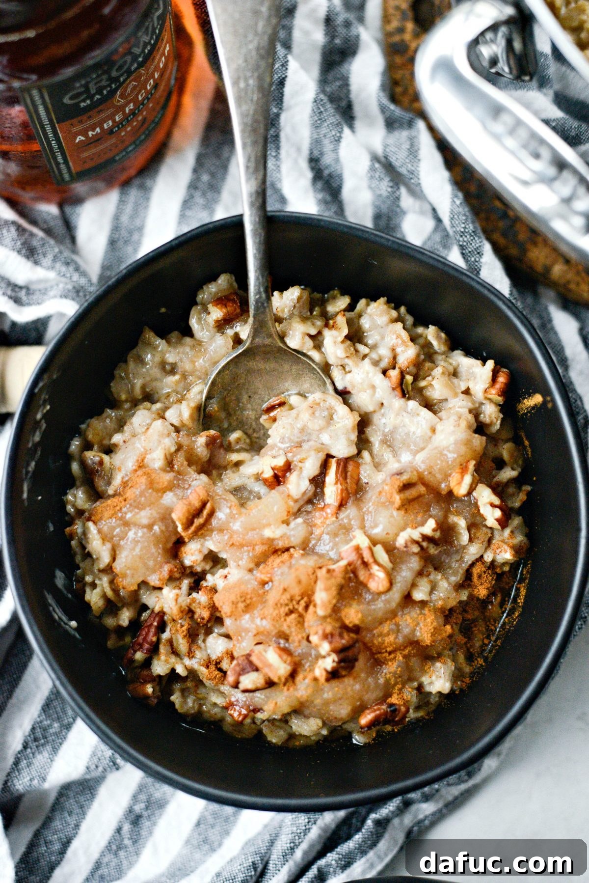 A beautifully presented bowl of Apple Chai Oatmeal, topped with fresh apple slices, pecans, and a swirl of maple syrup, exuding warmth and autumn comfort.