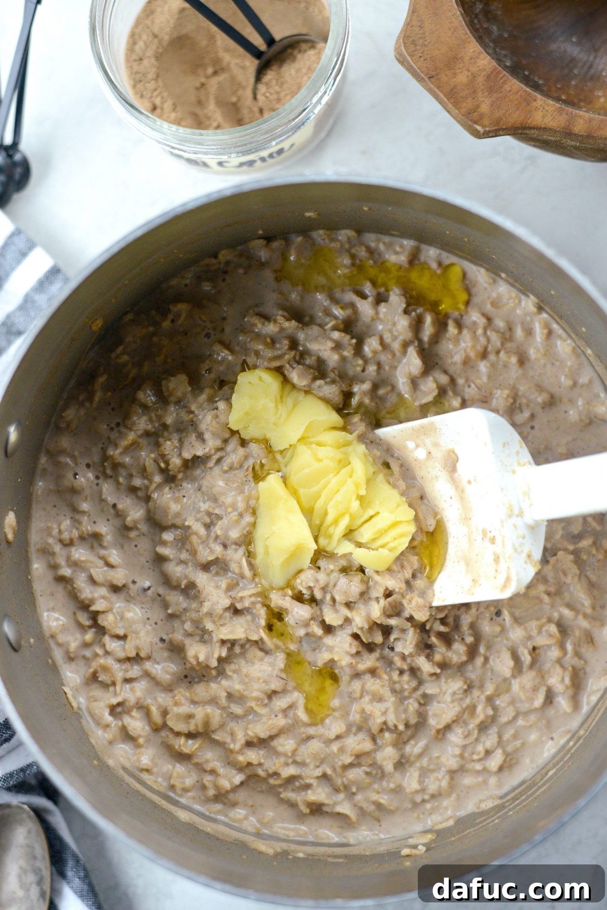 Stirring a pat of ghee or butter into the hot, creamy oatmeal until it melts completely.