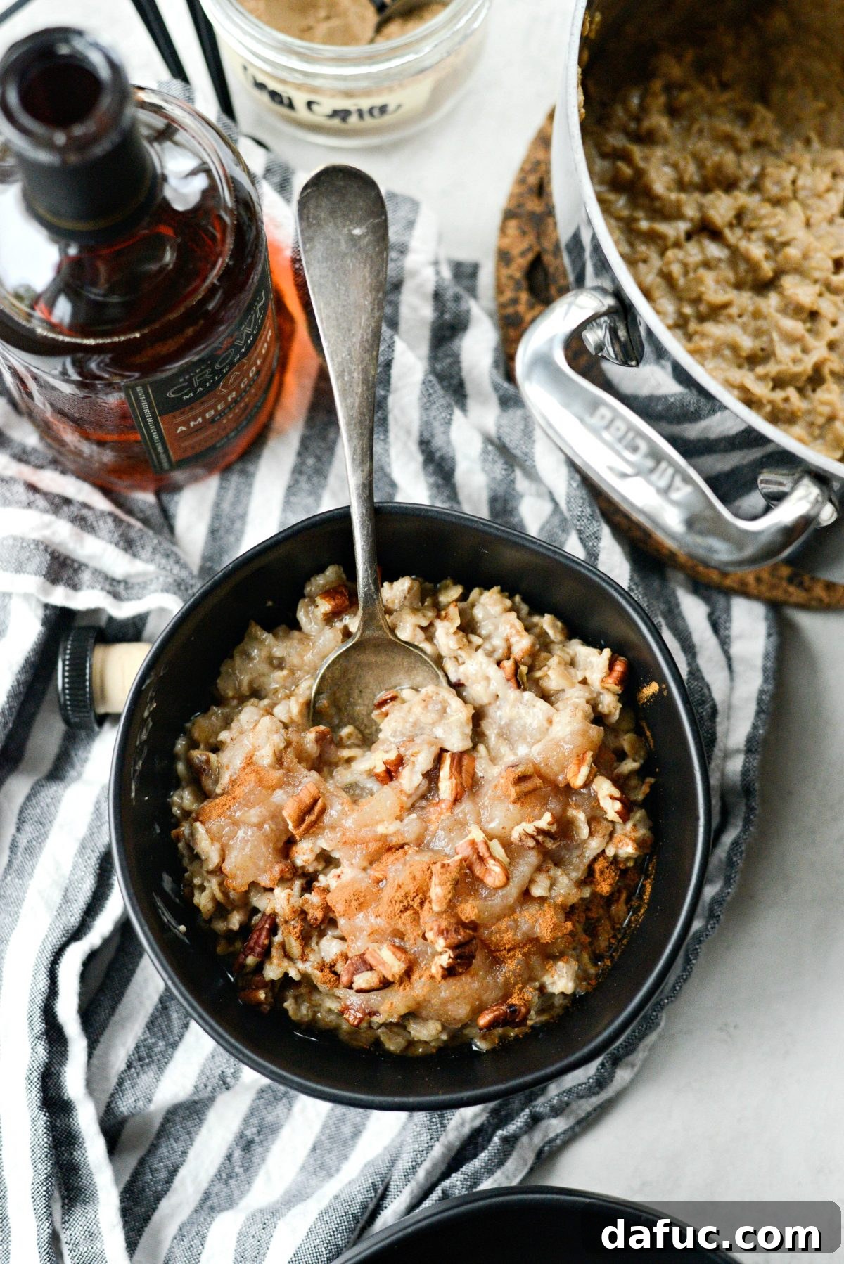 A spoon lifting a serving of creamy Apple Chai Oatmeal from a bowl, showcasing its texture and deliciousness.