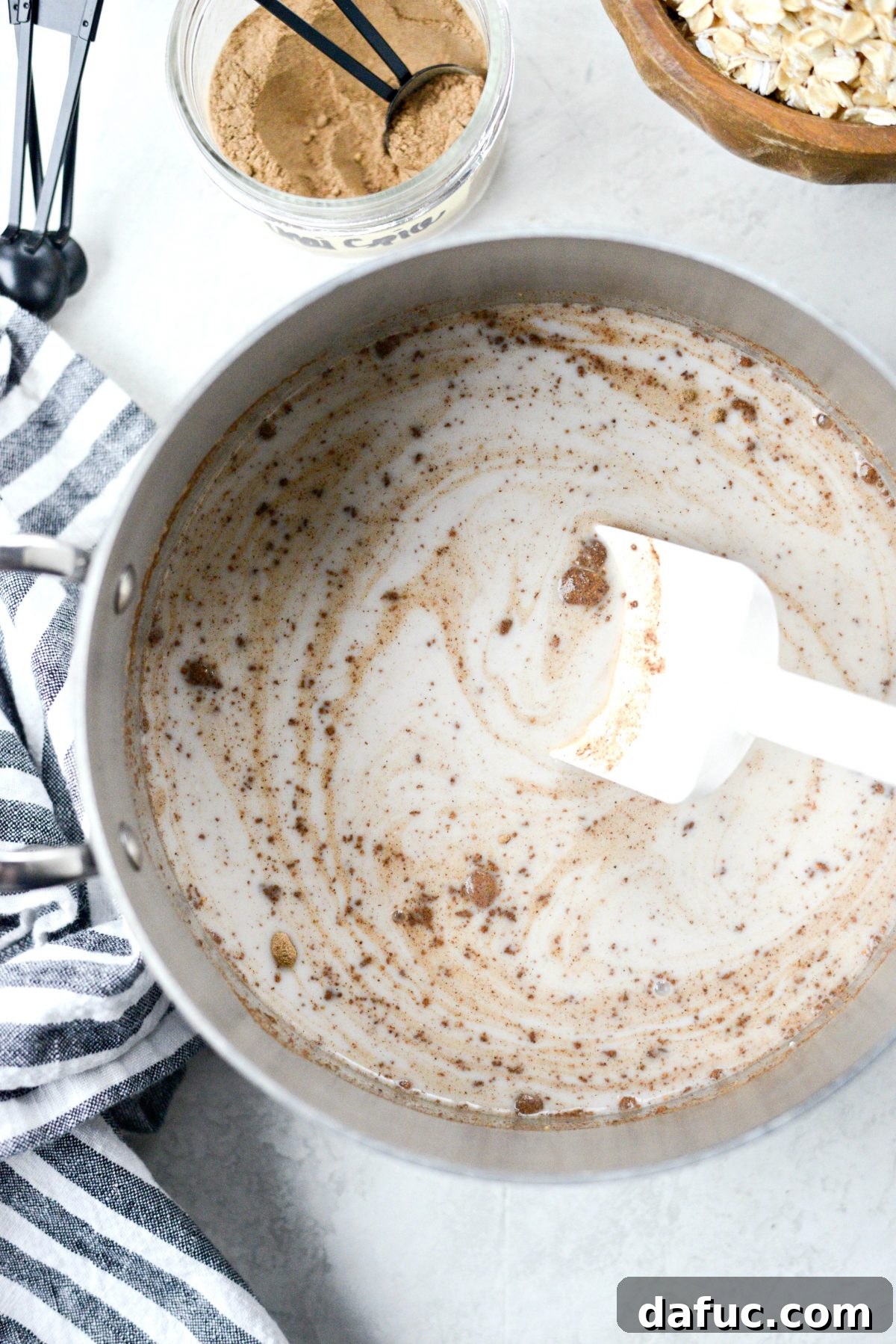 Stirring the milk, chai spice, and salt mixture in the saucepan as it heats.