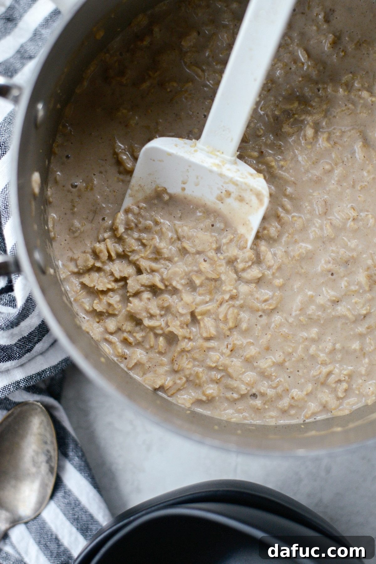 Close-up of the chai oatmeal thickening in the saucepan, showing its creamy texture.