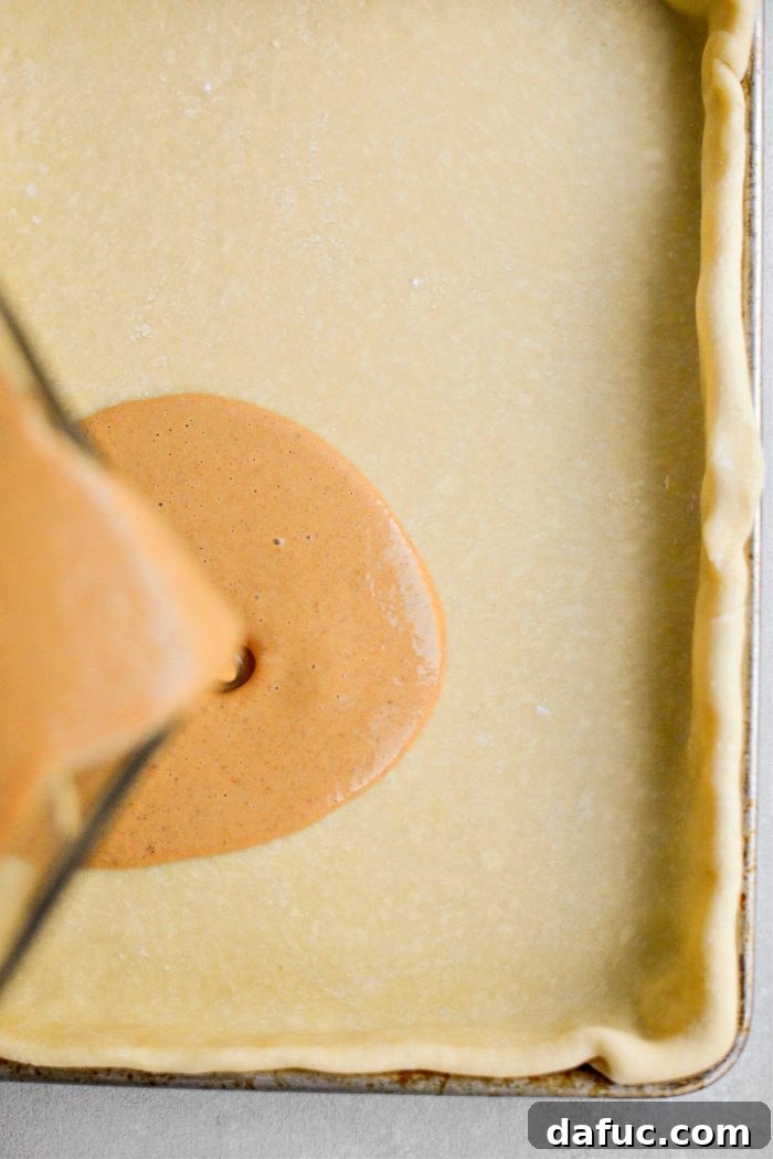 Sheet Pan Pumpkin Pie 13 Pouring the smooth pumpkin filling into the golden, partially baked pie crust