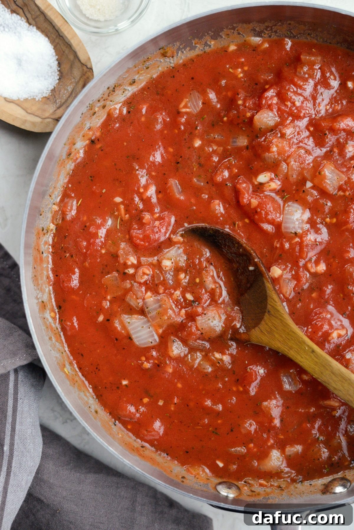 Sweet Butternut Marinara 13 San Marzano tomatoes being broken up with a spoon as sauce simmers