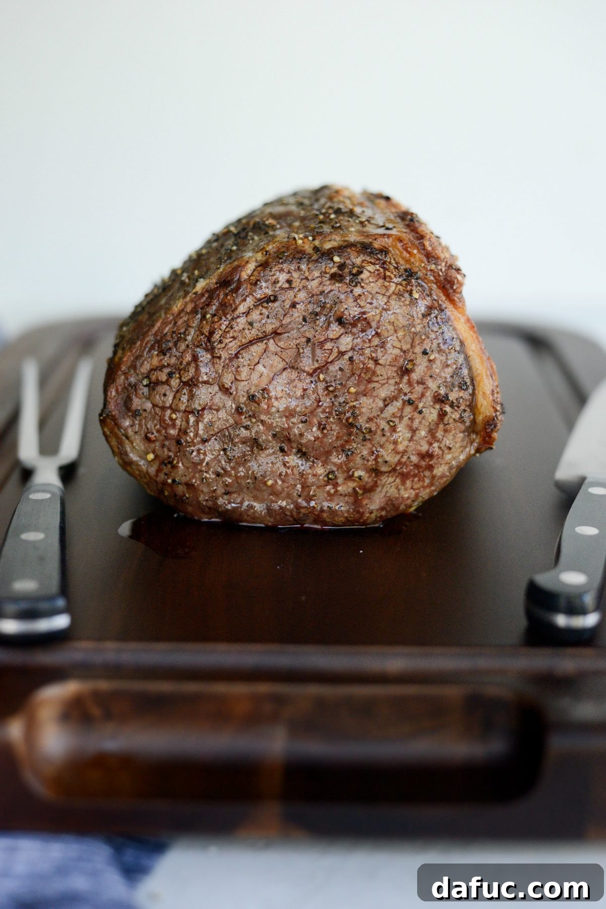 Roasted beef resting under foil before carving to retain its juices.