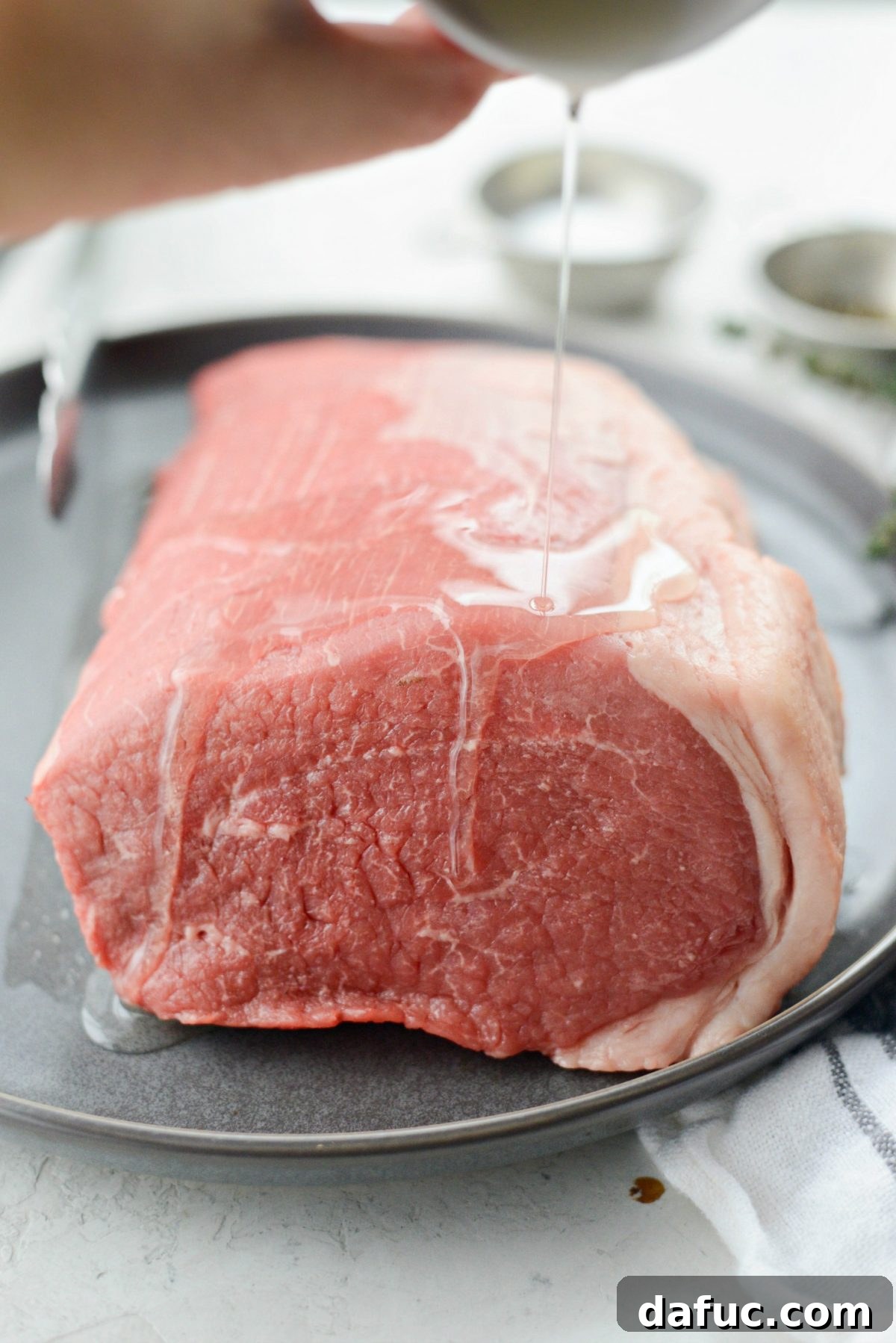 Ingredients for Easy Homemade Roast Beef, including fresh herbs and top round.