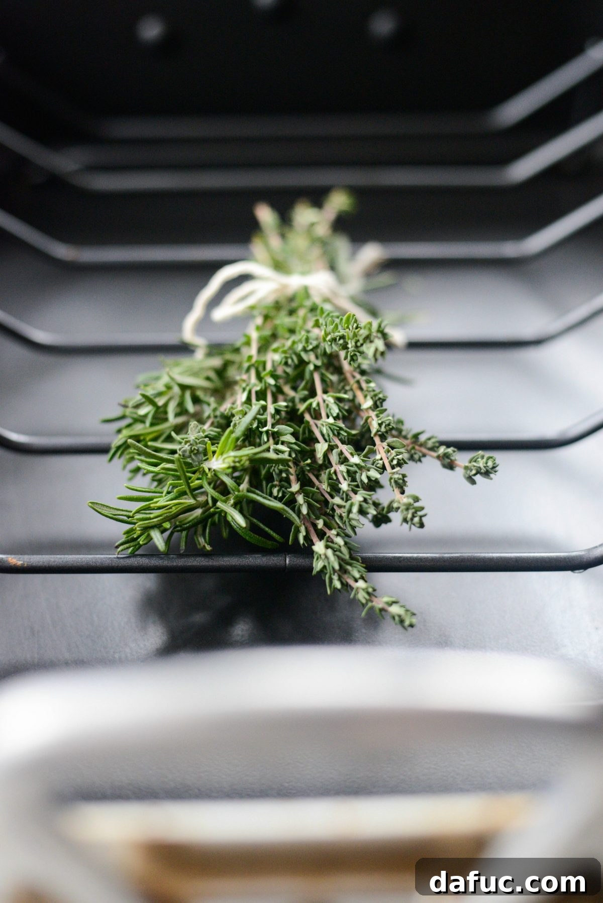 A bundle of fresh thyme and rosemary sprigs tied with kitchen string.