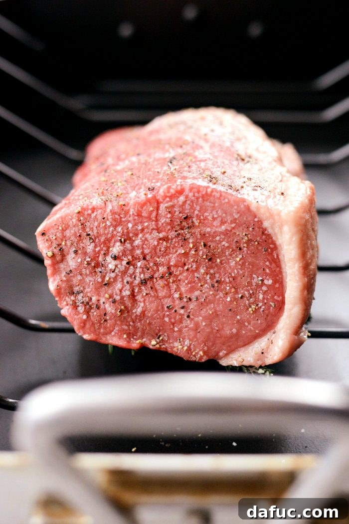 Placing the seasoned roast beef, garlic-side down, onto the herb bed in the roasting pan.