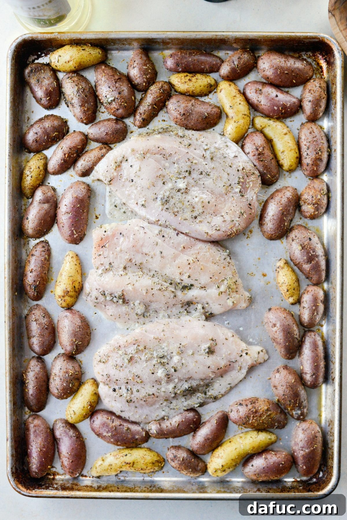 Chicken breasts added to the sheet pan with roasted potatoes