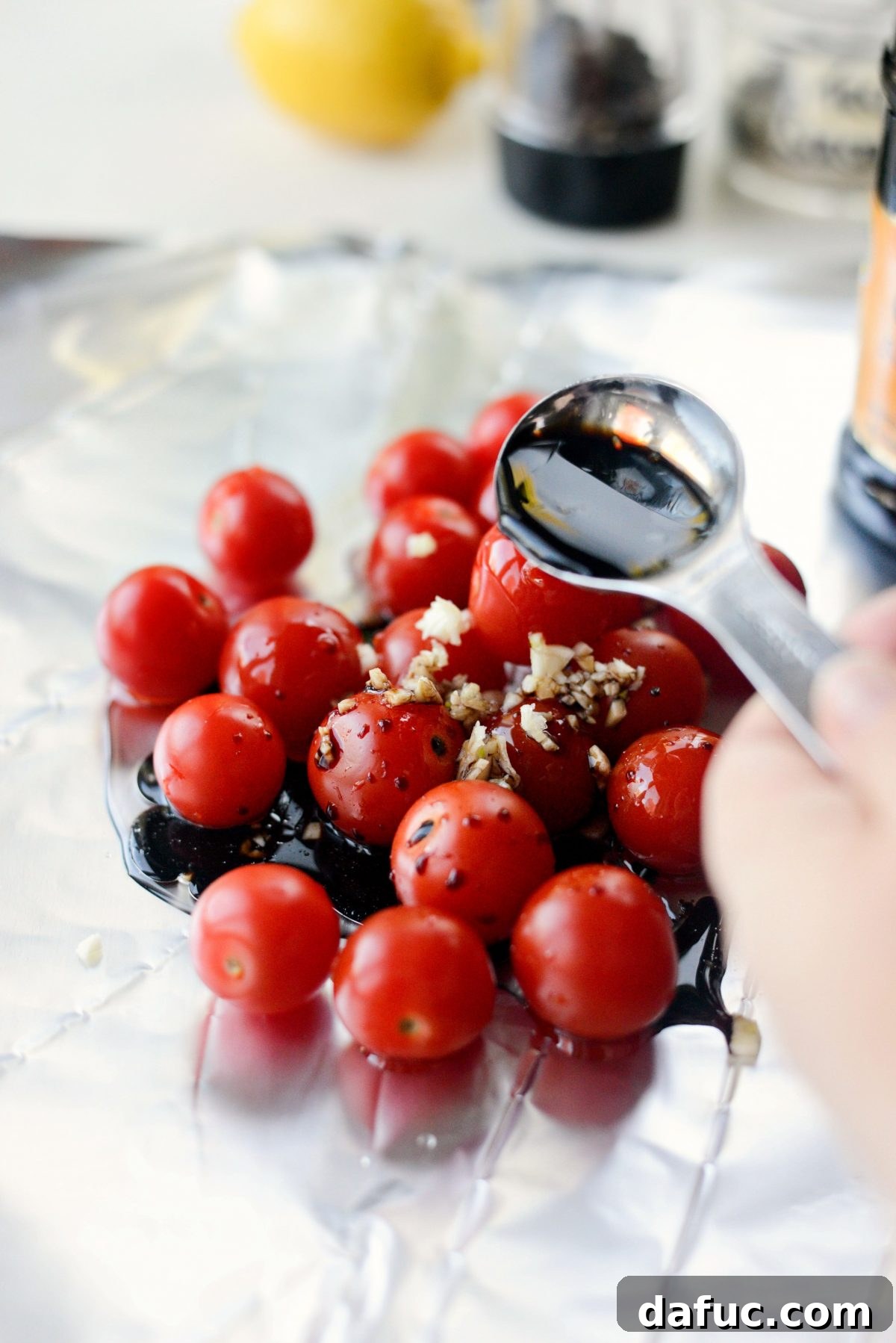Making tomato foil packet with cherry tomatoes, minced garlic, and balsamic vinegar
