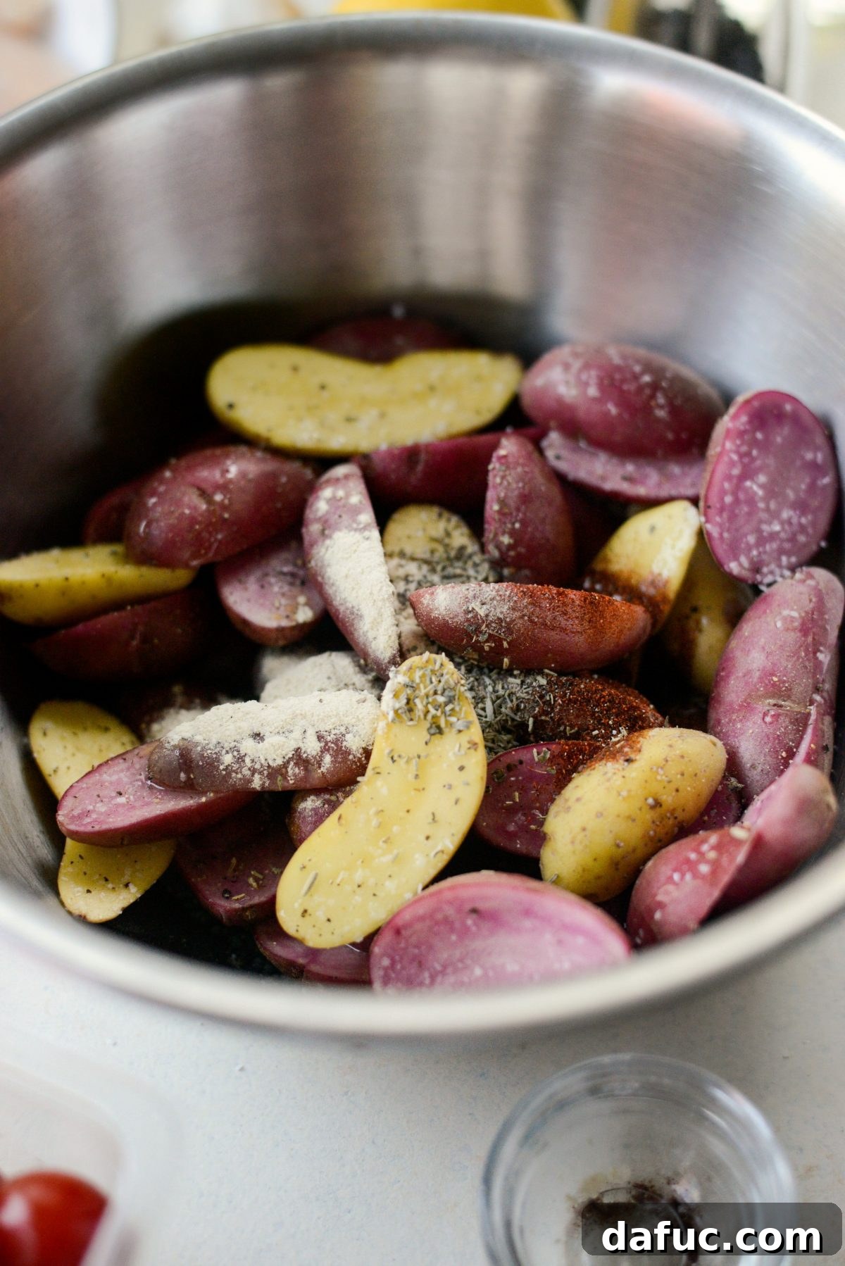 Seasoning halved fingerling potatoes with olive oil and spices