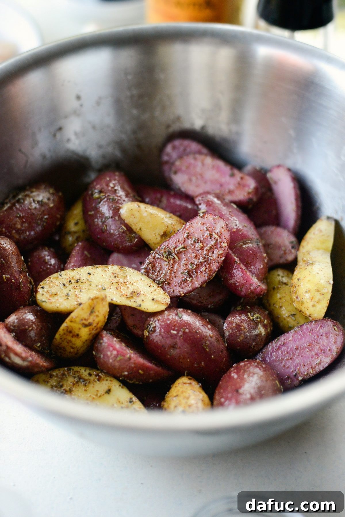Tossing fingerling potatoes to coat them in oil, herbs, and spices