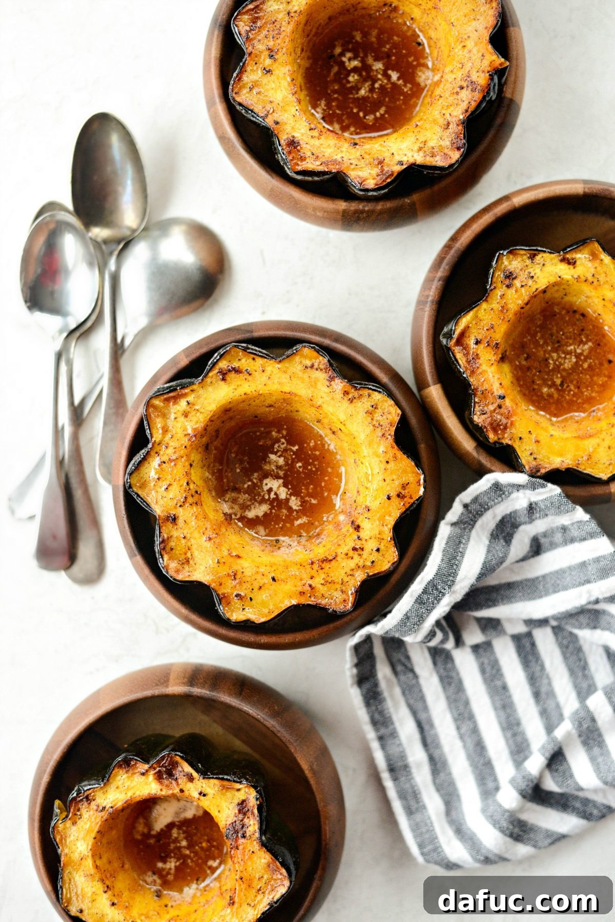 Golden-brown maple butter roasted acorn squash halves, glistening and caramelized, ready to be served as a festive holiday side dish.