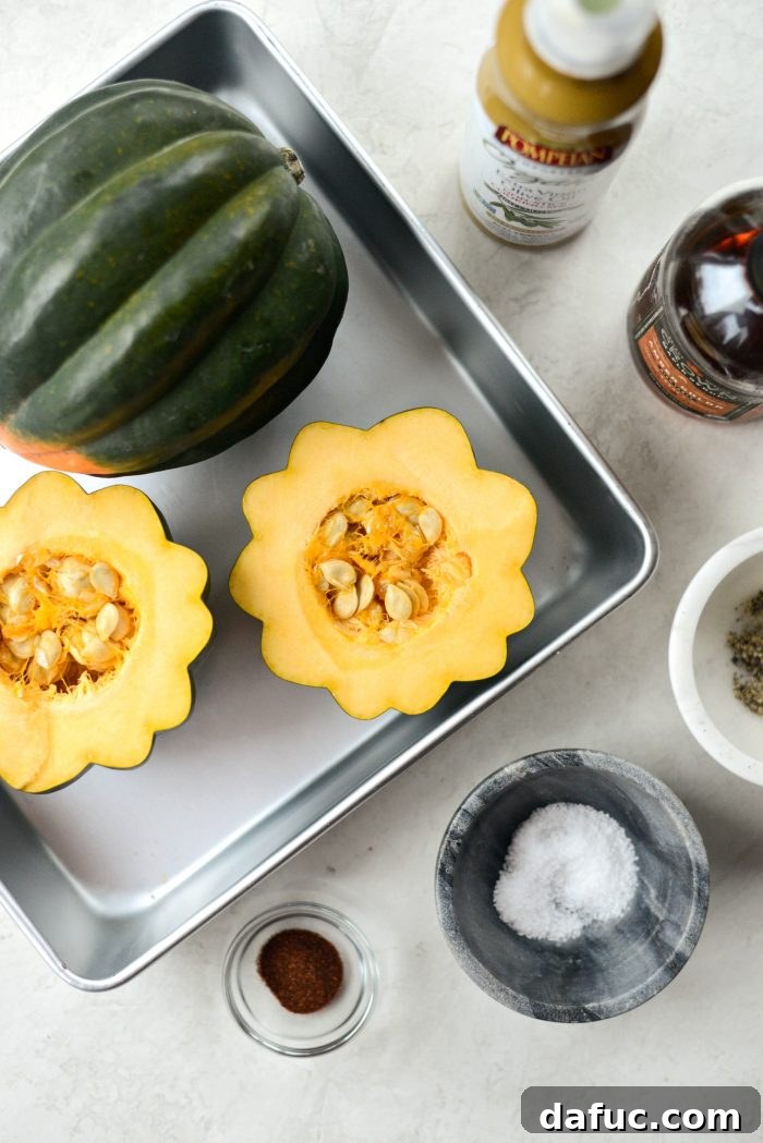 A selection of fresh ingredients laid out for maple butter roasted acorn squash, including acorn squash, butter, maple syrup, and spices.