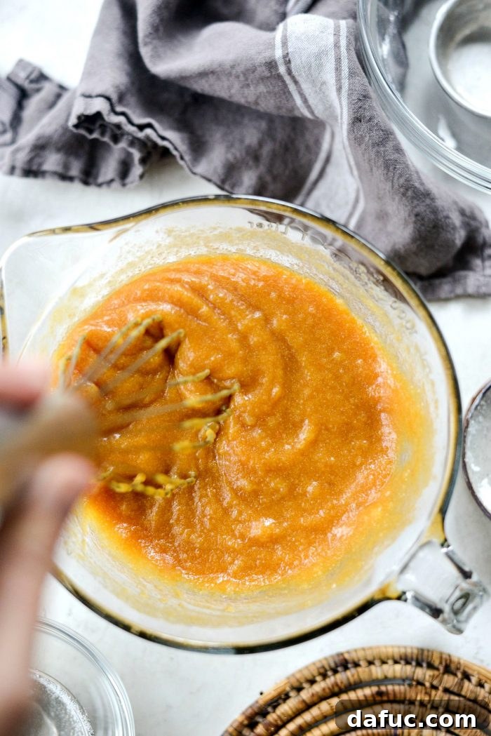 Spiced Pumpkin Ginger Loaf with Luxe Maple Brown Butter Glaze 7 Wet ingredients for pumpkin bread in a bowl, including pumpkin puree, eggs, melted butter, and sugars. Ready to be whisked.