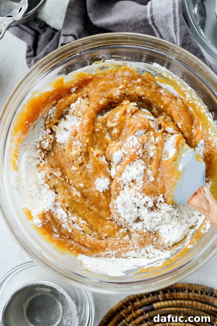 Spiced Pumpkin Ginger Loaf with Luxe Maple Brown Butter Glaze 9 Pumpkin mixture being poured into a bowl of dry ingredients for the bread batter. The next step in combining flavors.