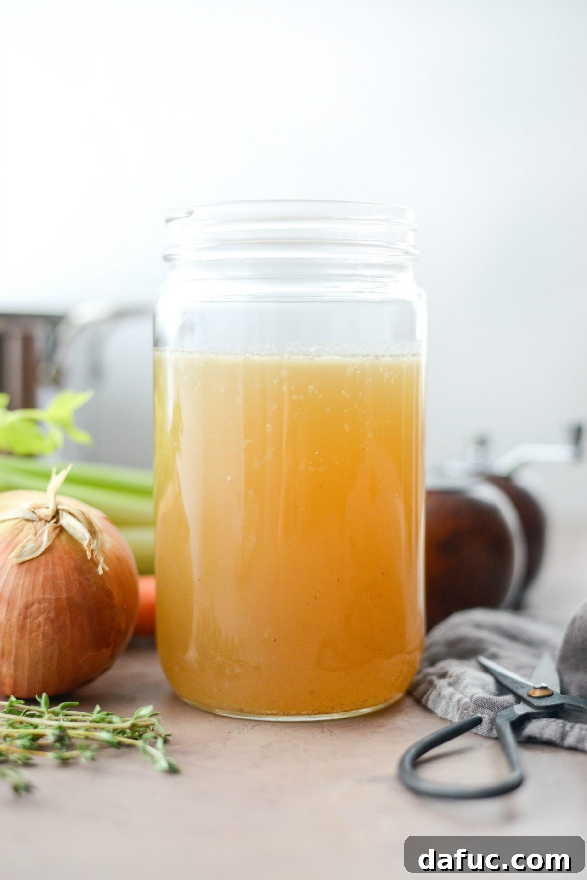 Homemade Turkey Stock, golden broth in a measuring cup with leftover turkey carcass ingredients