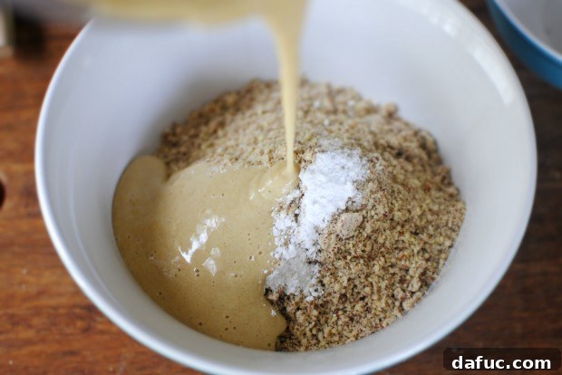 Pouring the banana mixture into the bowl with ground almonds