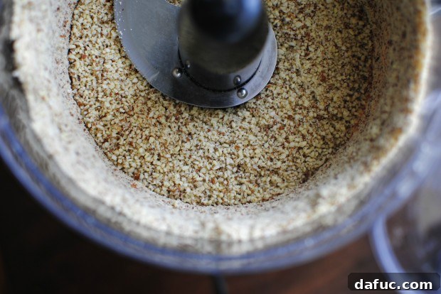 Food processor lid secured, ready to pulse almonds into fine meal