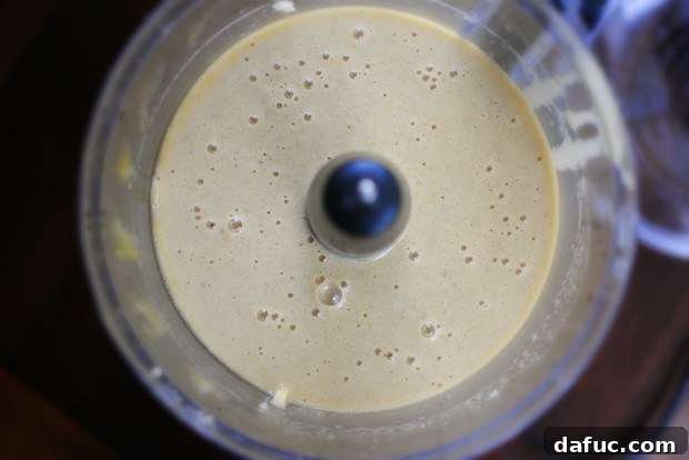 Smooth banana mixture in a food processor, resembling pancake batter