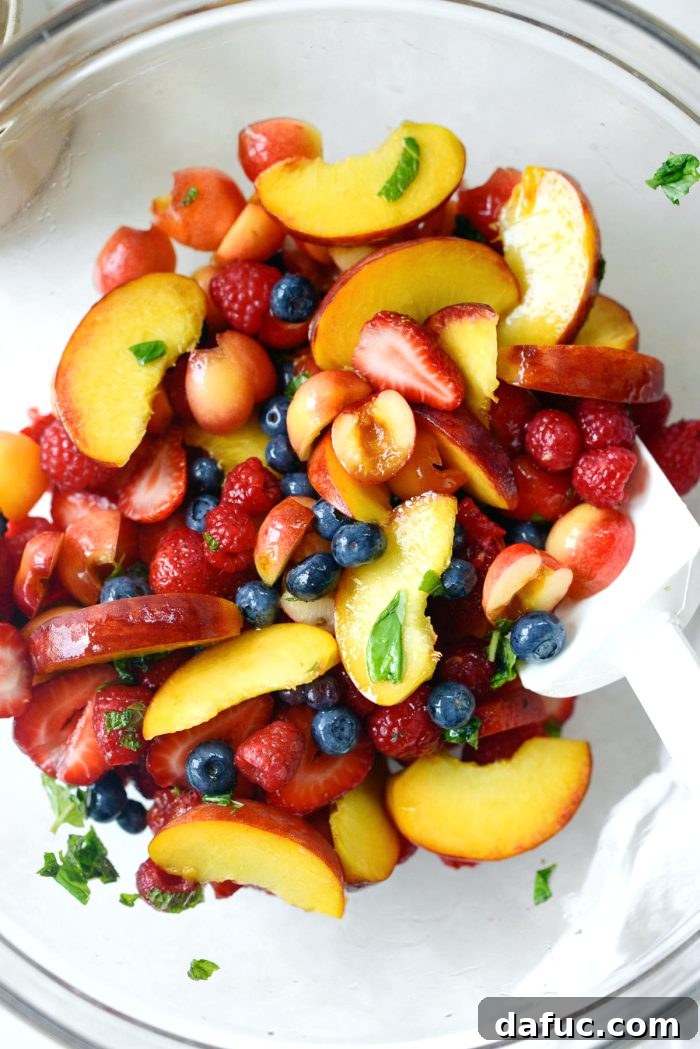 Gently tossing all the ingredients together in the mixing bowl to ensure an even distribution of dressing and flavors