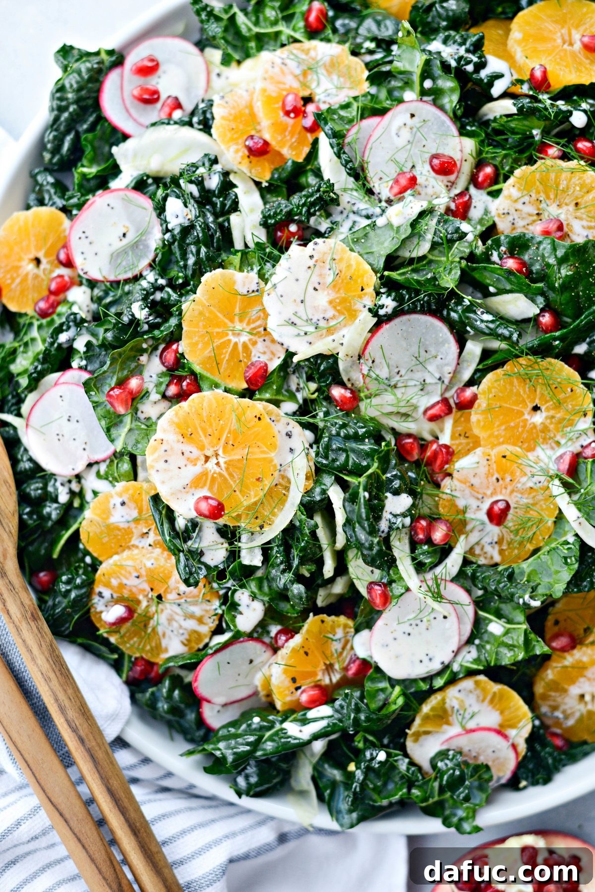 Winter Clementine Fennel and Kale Salad drizzled with dressing and pomegranate seeds