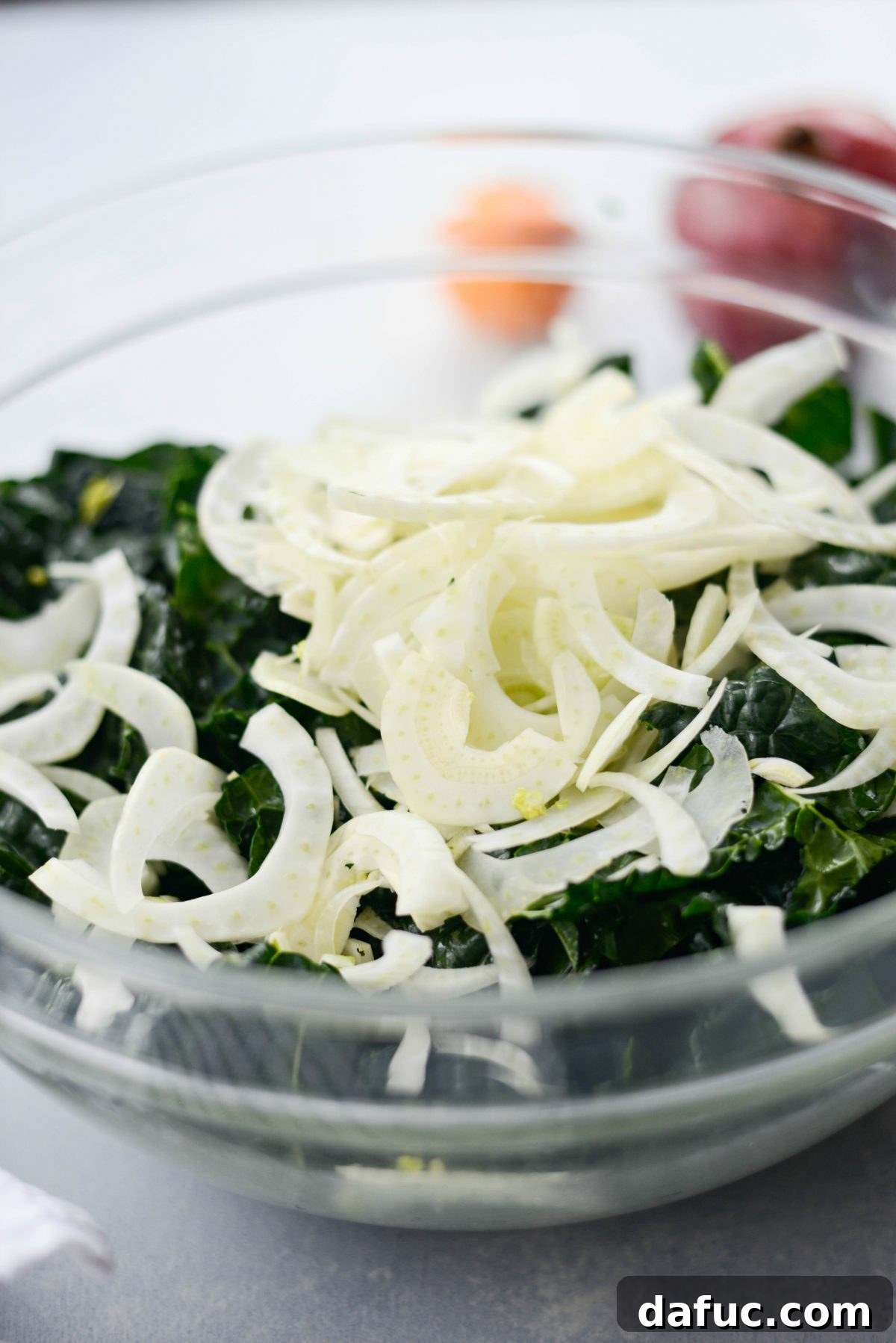 Adding thinly sliced fennel to the massaged kale