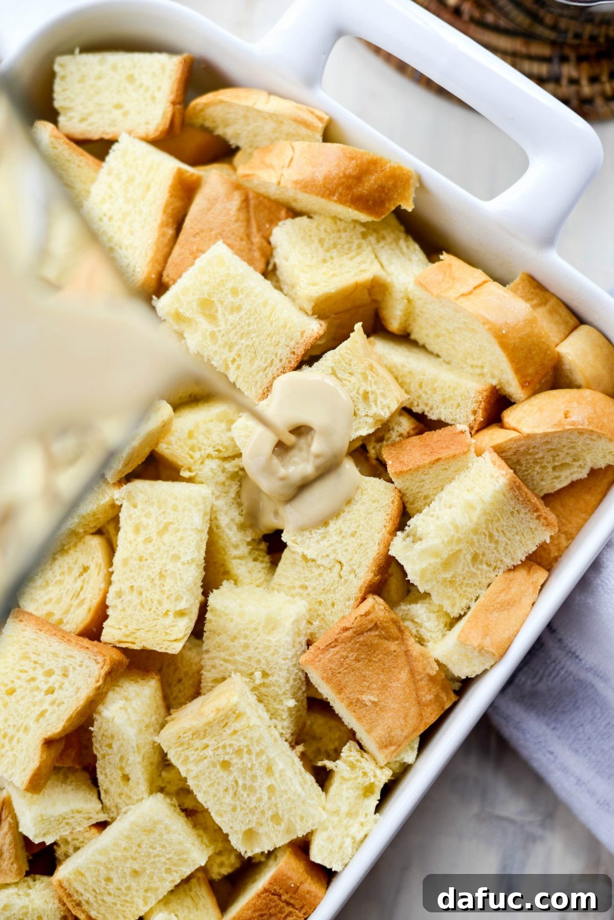 Pouring custard over cubed brioche in baking dish