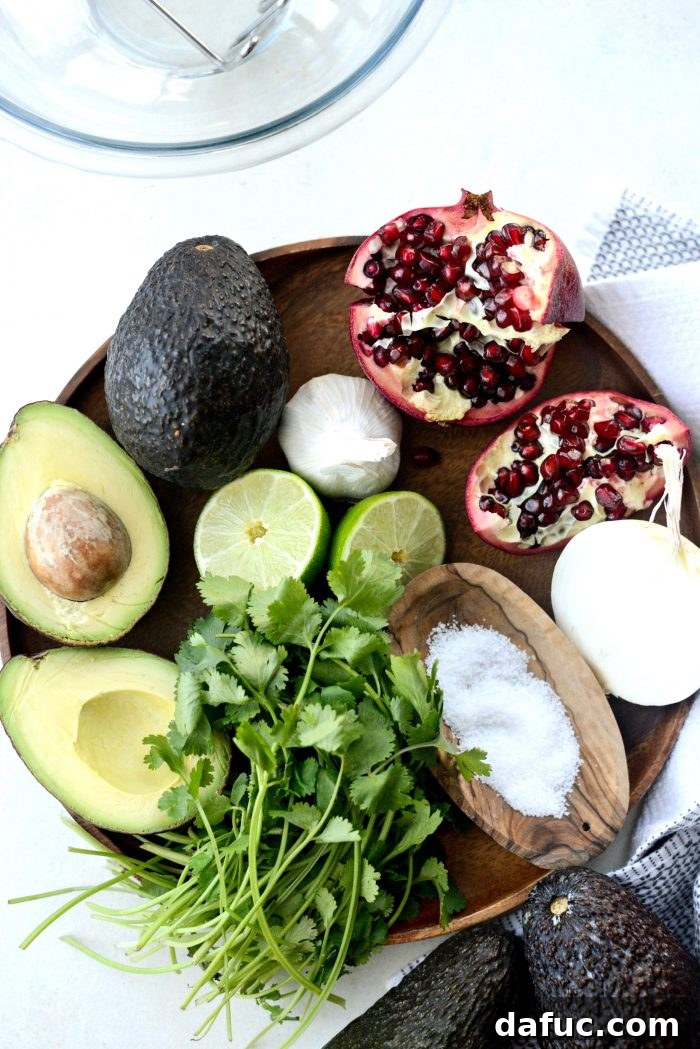 Fresh ingredients for Holiday Guacamole including avocados, lime, garlic, onion, cilantro, and pomegranate