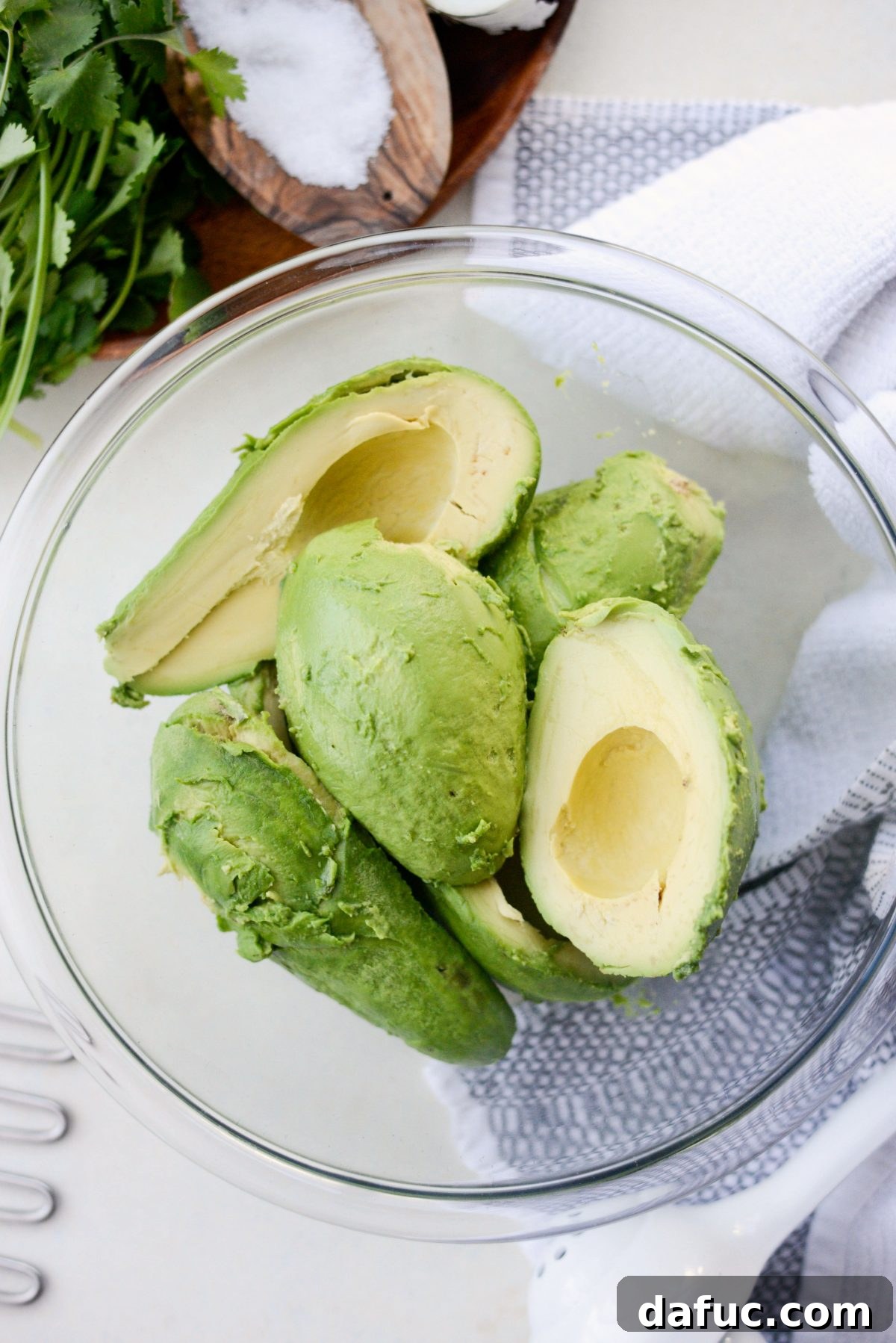 Four ripe Hass avocados in a mixing bowl, ready for mashing