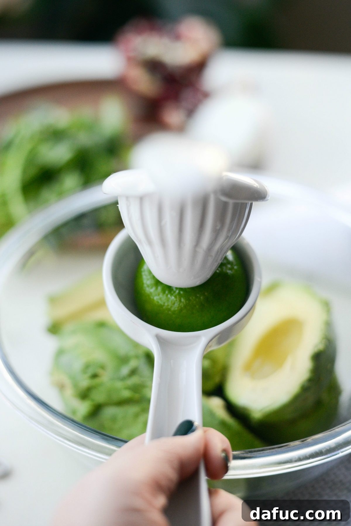 Squeezing fresh lime juice over scooped avocado flesh in a bowl