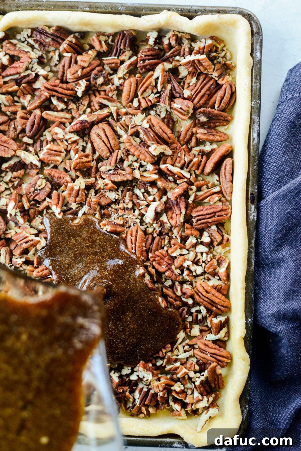 Pouring the gingerbread pecan pie filling over the pecans in the crust