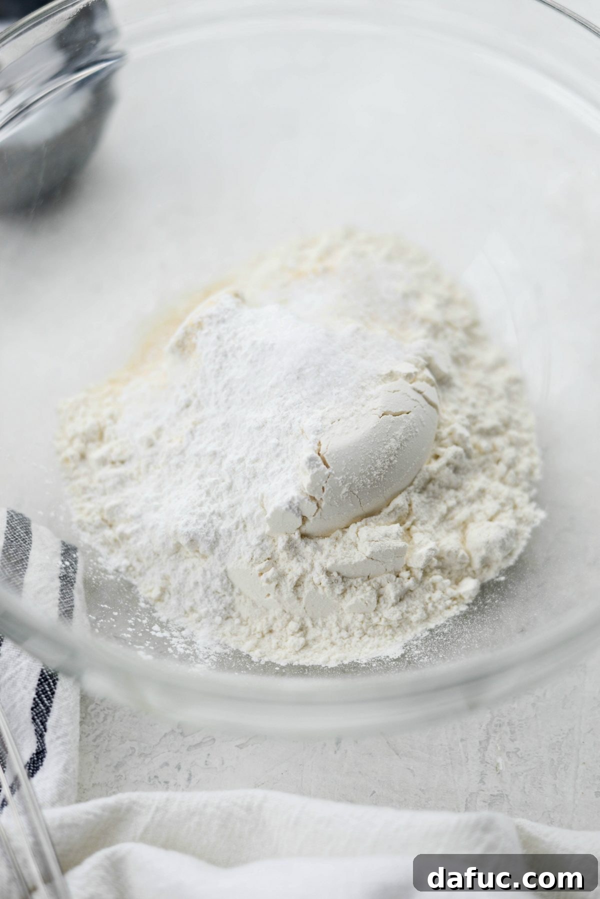 Adding dry ingredients, flour, baking powder, and spices, to a mixing bowl