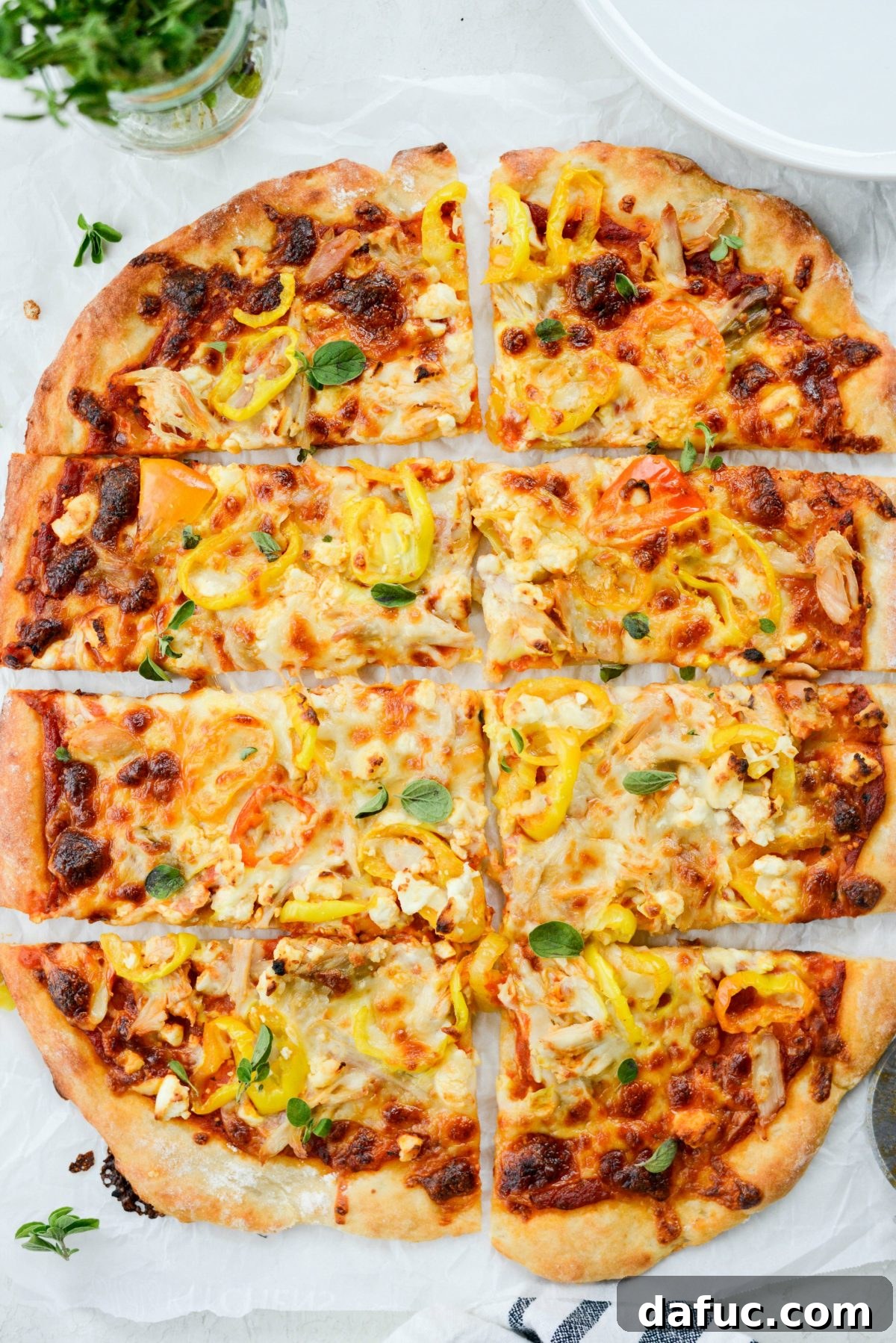 A beautifully presented Spicy Chicken Feta Pizza on a round serving tray, garnished with fresh oregano